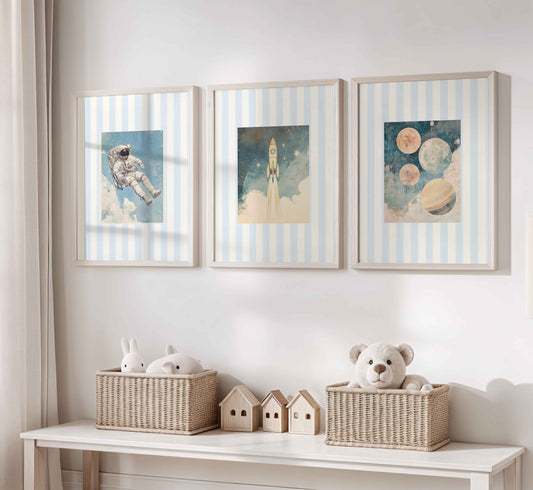Vintage nursery wall art set with an astronaut in space, a rocket launching into the sky, and planets including Saturn and several moons on a blue striped background