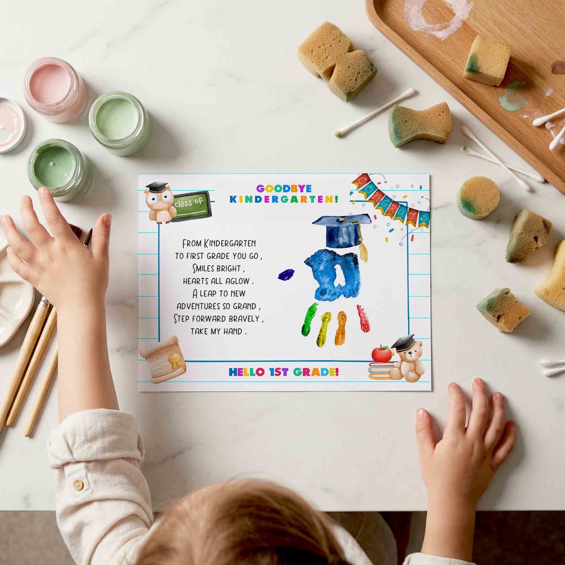 Child's hands reaching towards a 'Goodbye kindergarten' printout on a table with educational materials.