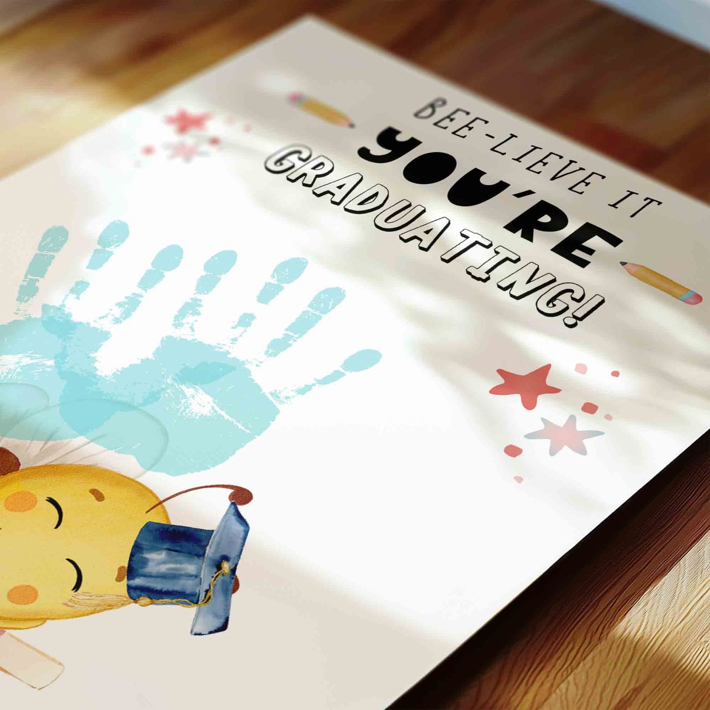 Graduation-themed poster with handprints and text on a wooden floor.