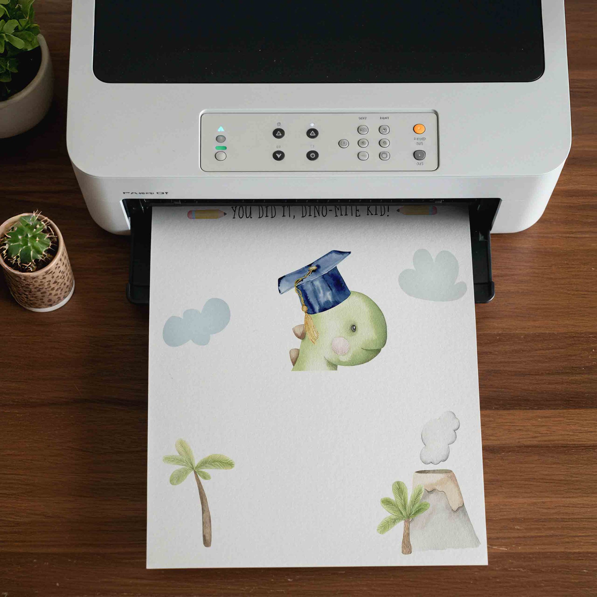 Printer on a wooden surface with a sheet of paper featuring cartoon dinosaur and volcano illustrations.