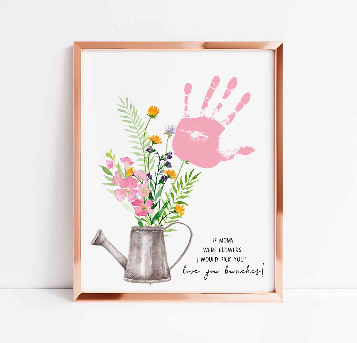 Framed artwork with pink handprint, flowers, and a watering can on a white background